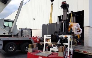 40,000 lb. Injection blow molding machine unloaded with crane and Versa-Lifts, dollied through plant and placed in location